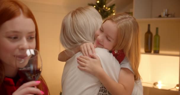 Маленькая блондинка обнимает бабушку и дедушку на рождественском семейном ужине — стоковое видео