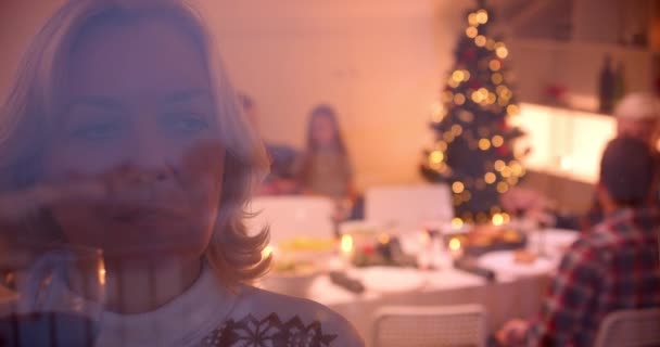 Sad grandmother looks out the window Christmas dinner family behind glass — ストック動画
