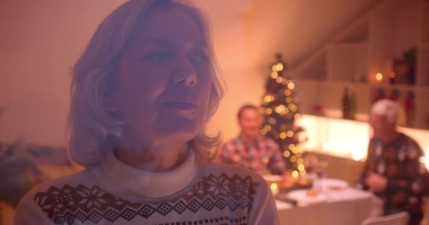 Grootmoeder kijkt uit het raam Kerstmis familie diner avond achter glas — Stockvideo