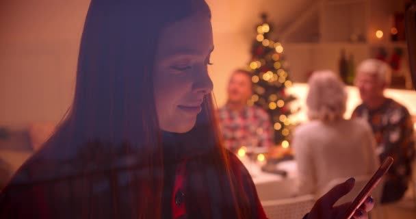 Redhead teenager girl using smartphone. Smiling. Laughing. Christmas behind the glass. — ストック動画