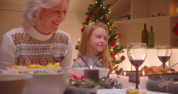 Маленька кавказька дівчинка онука з бабусею різдвяна вечеря сімейна посмішка — стокове відео
