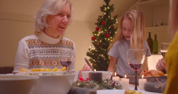 Küçük beyaz kız torun kız kardeşinin Noel eğlencesini gösteren bir akıllı telefon kullanıyor. — Stok video