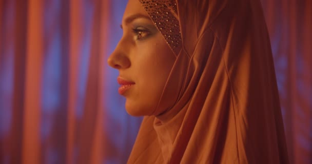 Blank meisje zwart hijab neon make-up portret licht nacht paars achtergrond — Stockvideo