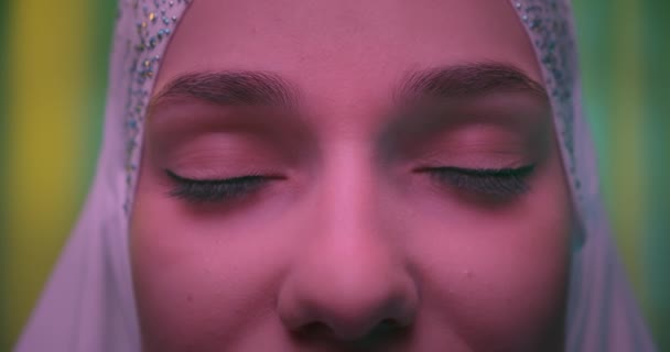 Close-up van de ogen in witte hijab Kaukasisch jong meisje groene achtergrond neon licht — Stockvideo
