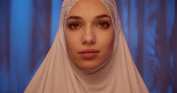 Белая девушка белый хиджаб неоновый макияж портрет светло-синий фон — стоковое видео