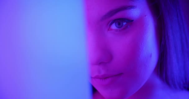 Close-up Girl in neon se uită la camera de după colț lumina noapte portret flirt — Videoclip de stoc