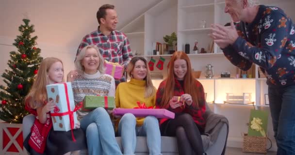 Große Familie freut sich über Weihnachtsgeschenke, wenn sie auf dem Sofa sitzt und lacht — Stockvideo