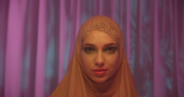 Kaukasische junge Mädchen im Hijab neonorange Farbe rosa Hintergrund Porträt Make-up Blick in die Kamera — Stockvideo