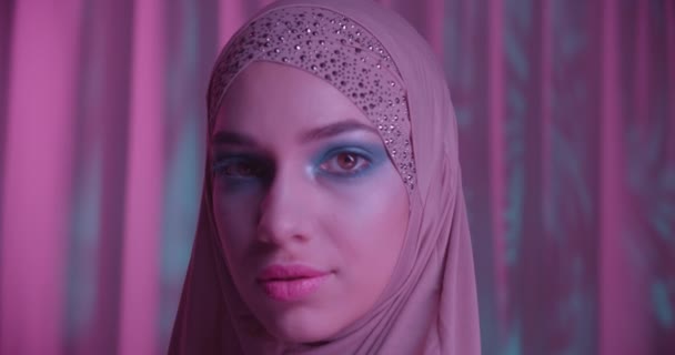 Menina branca em hijab neon cor roxa fundo retrato maquiagem olhando para a noite de sombra da câmera — Vídeo de Stock