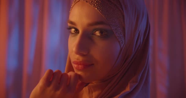 Biały piękne dziewczyna w hidżab neon pomarańczowy kolor wieczór zachód słońca tło portret dotyka twarz patrzeć w bok — Wideo stockowe