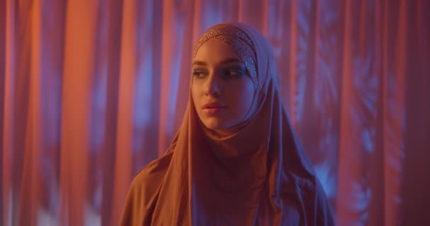 Καυκάσιος όμορφο κορίτσι σε χιτζάμπ νέον πορτοκαλί χρώμα βράδυ ηλιοβασίλεμα φόντο πορτρέτο αγγίζει σκέψης πρόσωπο ματιά πλάγια — Αρχείο Βίντεο