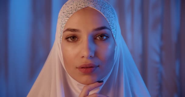 Retrato de chica caucásica en blanco hijab neón luz mirada a la cámara tentación noche maquillaje — Vídeos de Stock