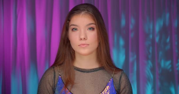 Retrato de menina caucasiana em neon luz vestido roxo fundo confiante olhar sério — Vídeo de Stock