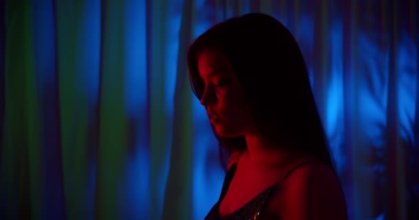 Retrato de una joven chica caucásica neón azul oscuro fondo noche noche luz roja imagen silueta — Vídeos de Stock