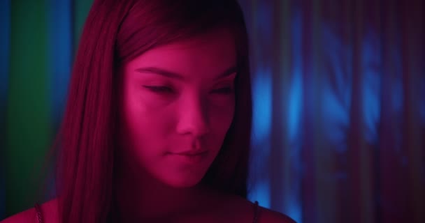 Крупним планом дівчина портрет рожевий світло неонова мода радість усміхнений флірт синій фон скромний — стокове відео