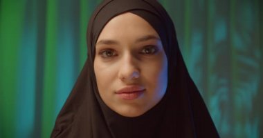 Beautiful confident girl in black hijab neon night green background shadow image make-up confident look