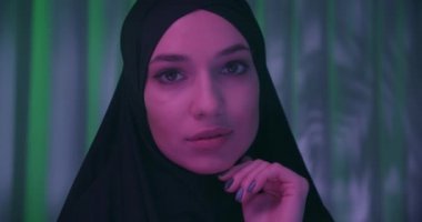Beautiful confident girl in black hijab neon night green tropical background shadow image make-up purple color confident look