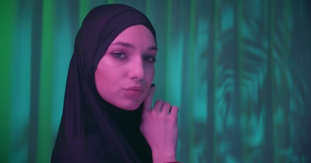 Vacker självsäker flicka i svart hijab neon natt grön tropisk bakgrund skugga bild make-up lila färg profil visa tur — Stockvideo