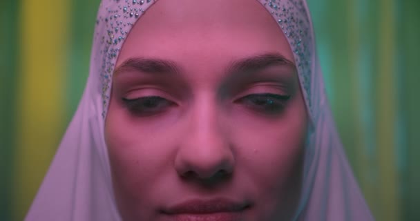 Nahaufnahme Schöne selbstbewusste Mädchen im weißen Hijab neongrünen Glitzerhintergrund — Stockvideo