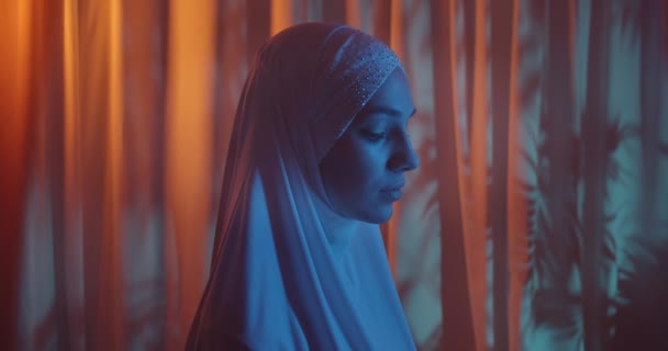 Gyönyörű portré magabiztos lány fehér hidzsáb neon zöld háttér csillogó nézet profil make-up viszont kék fény kilátás profil — Stock videók