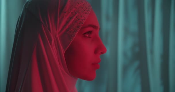 Close-up Linda menina confiante retrato em um branco hijab neon verde fundo brilho vista perfil make-up retrato vermelho luz perfil — Vídeo de Stock