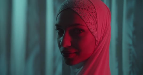 Close-up Hermosa chica confiada retrato en un hijab blanco neón fondo tropical brillo delicado maquillaje vuelta luz roja perfil rojo haz — Vídeo de stock