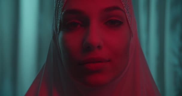 Close-up Beautiful portrait confident portrait girl in white hijab profile neon tropical background sensual make-up turn red moving light beam shadow silhouette — Stock Video