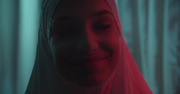 Nahaufnahme Schönes Porträt selbstbewusstes Porträt Mädchen in weißem Hijab Profil Neon Hintergrund Make-up wiederum rotes Licht Strahl Schatten Silhouette Lächeln Freude — Stockvideo