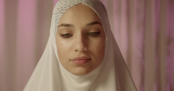 Retrato caucasiano confiante retrato menina no branco hijab dia luz creme fundo brilho make-up confiante olhar brilho — Vídeo de Stock