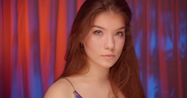 Portrait of caucasian beautiful confident girl neon light look at camera bare shoulders — Stock Video