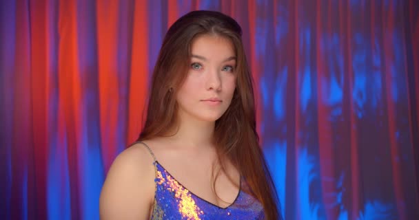 Portrait caucasian beautiful confident girl neon light look at camera bare shoulders sparkle shine background — Stock Video