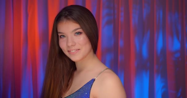 Portret Kaukasisch mooi zelfverzekerd meisje neon licht kijken naar camera kale schouders schitteren glans achtergrond glimlach — Stockvideo