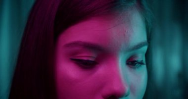 Kafkasyalı güzel, kendine güvenen bir kızın portresi. Neon ışığı. Kameranın arka planına bakın. Akşam şefkati modeli.
