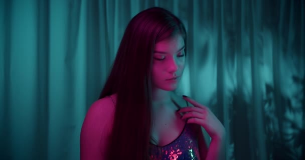 Portré kaukázusi gyönyörű magabiztos lány neon fény néz kamera háttér este érzékenység modell divat lila sugár haj — Stock videók
