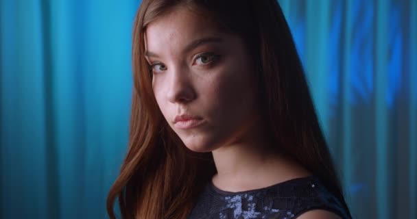 Närbild ledsen kaukasiska unga flicka porträtt ser blå bakgrund — Stockvideo
