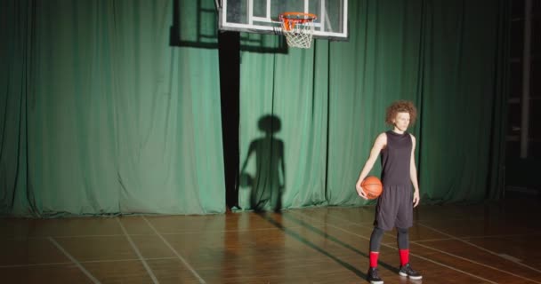 Lockige Basketballerin bereitet ernsten Schatten helles Licht spielt Dunkelheit Zuversicht blickt nach vorne — Stockvideo