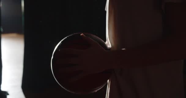 Joven jugador de baloncesto caucásico preparándose para ir detrás del escenario oscuro silueta rayo de luz confianza bola entrenamiento — Vídeos de Stock