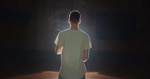 Basketball player silhouette plays with a ball twists on a finger a shadow darkness back view — Stock Video