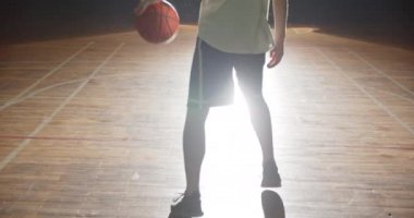 Basketbolcu beyaz tişörtlü siluet parmak gölgesinde bir top bükülmesiyle oynar.