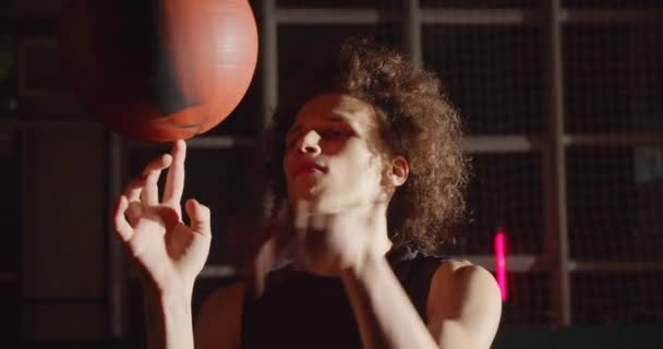 Joven peludo caucásico jugador de baloncesto retrato preparándose silueta gira la pelota en su dedo brillante luz sombra truco entrenamiento profesional — Vídeos de Stock