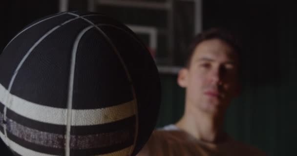 Популярний кавказький портрет баскетболіста з кошиком на задньому плані серйозно впевнений, що він виглядає як біла футболка. — стокове відео