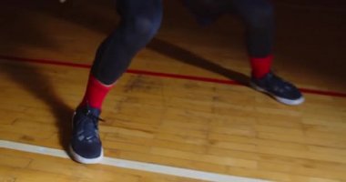 Bacakları yakın plan. Kıvırcık saçlı, beyaz basketbolcu. Profesyonel karanlık ışık huzmesi.