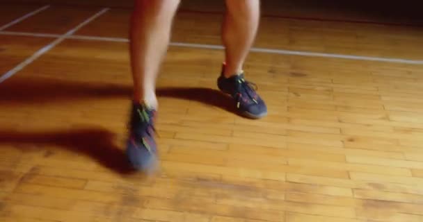 Γκρο πλαν πόδια ενός καυκάσιου μπασκετμπολίστα ντρίμπλαρε μια μπάλα επαγγελματική σκοτεινή κάμερα ακτίνα φωτός — Αρχείο Βίντεο