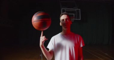 Yakın plan Kafkas genç basketbolcu portresi kırmızı ışık demeti siyah sepet arka plan numaraları top ile