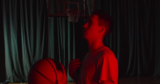 Jong portret van een Kaukasische basketbalspeler met een rood licht basketbal op een zelfverzekerde achtergrond warming up klaar — Stockvideo