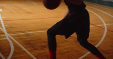 Genç kıvırcık profesyonel basketbolcu parke oynuyor. Topu potaya atıyor. Gece karanlığına, silüete.