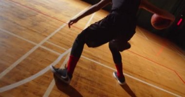 Genç kıvırcık profesyonel basketbolcu topu potaya fırlatıyor. Gece karanlığının silueti, yakın plan sallanıyor.