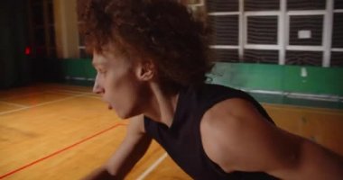 Genç kıvırcık profesyonel basketbolcu topu potaya fırlatıyor. Gece karanlığının gölgesine. Yakın çekim dayanıklılığı sürüyor.