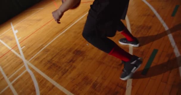 Jeune joueur de basket professionnel bouclé joue lancer la balle dans le panier nuit obscurité silhouette vue arrière dribble close-up parquet — Video