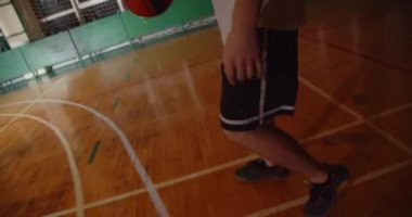 Beyaz tenli genç basketbolcu topu potaya fırlatıyor. Gece karanlığının gölgesine. Yakın plan parke dayanıklılığı sürüyor.